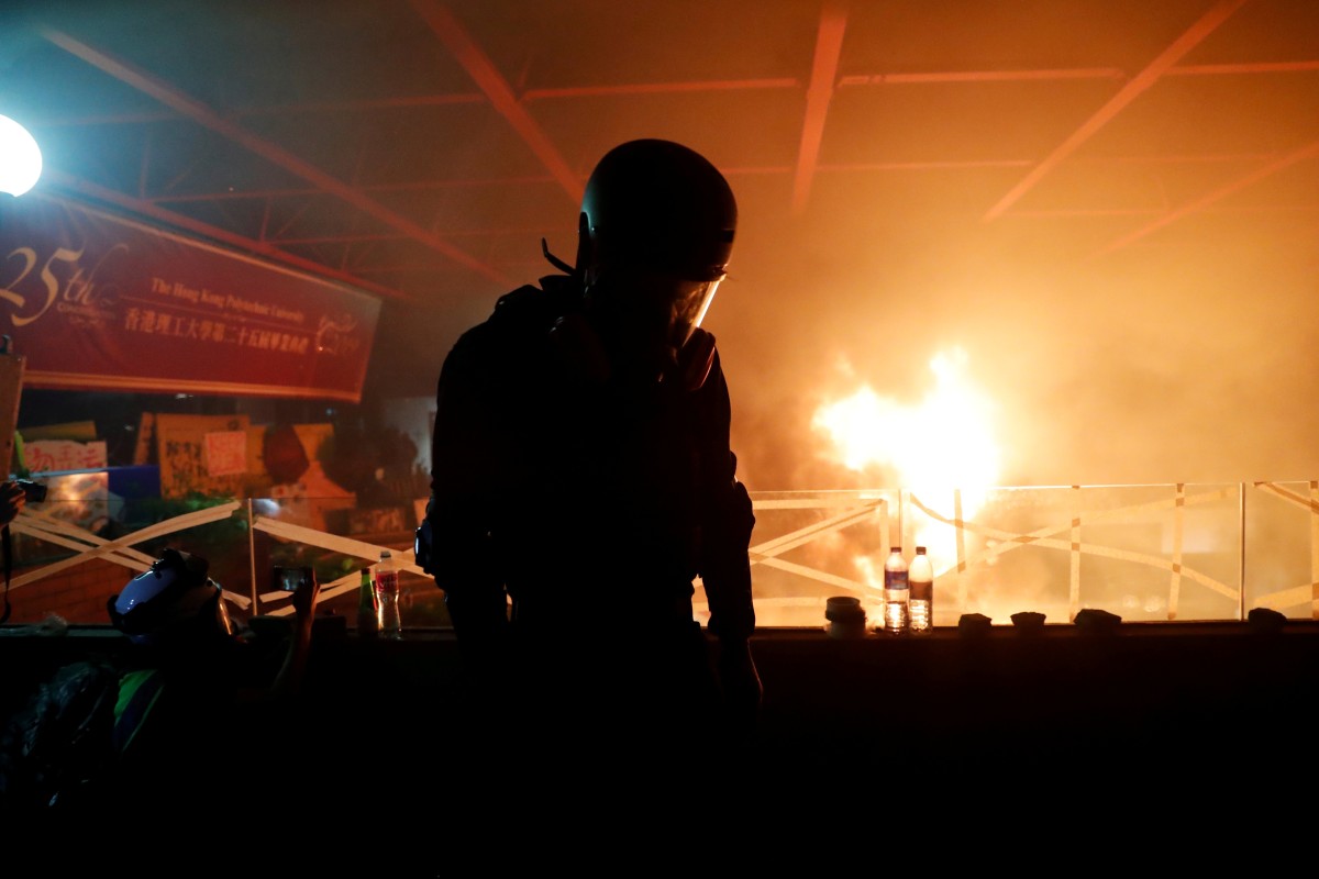 An anti-government protester watches as a fire rages at the entrance to Polytechnic University.