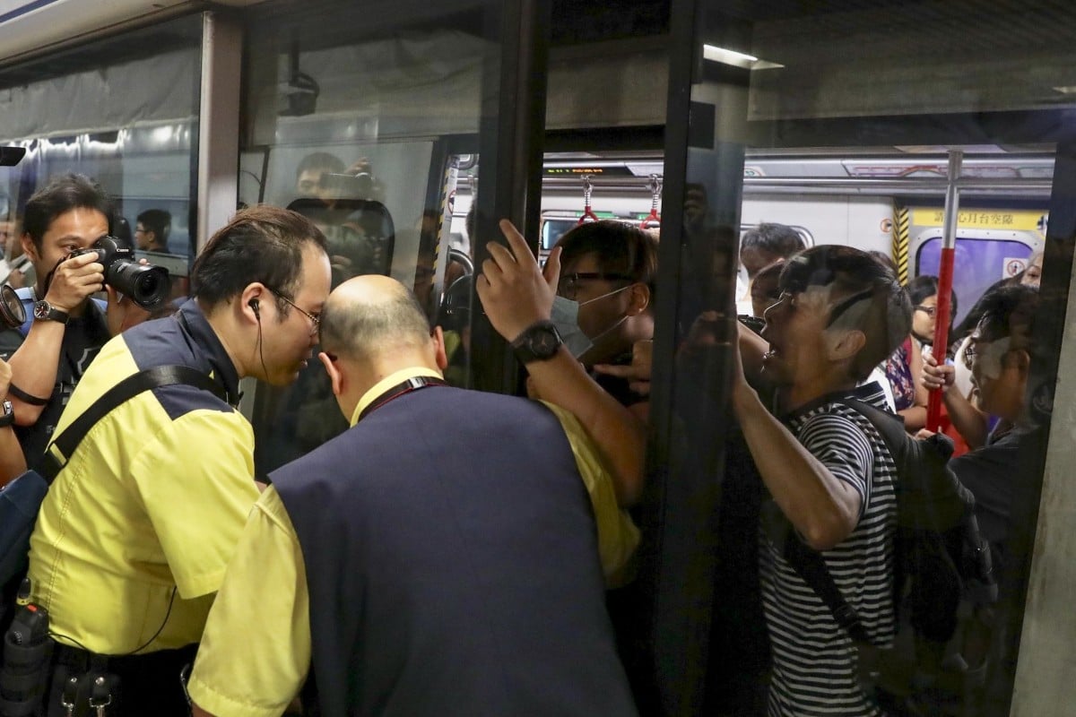 Protesters prevent the doors of a train closing as MTR staff try to stop them at Admiralty station.