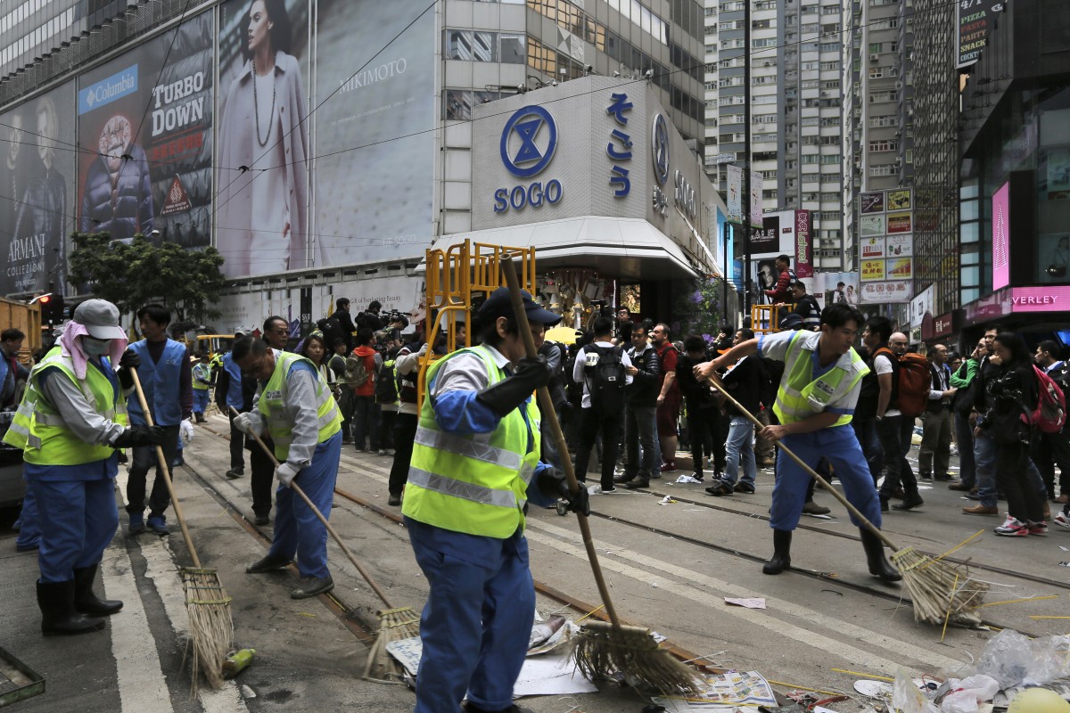 Workers sweep after police cleared barricades and tents at Causeway Bay today.