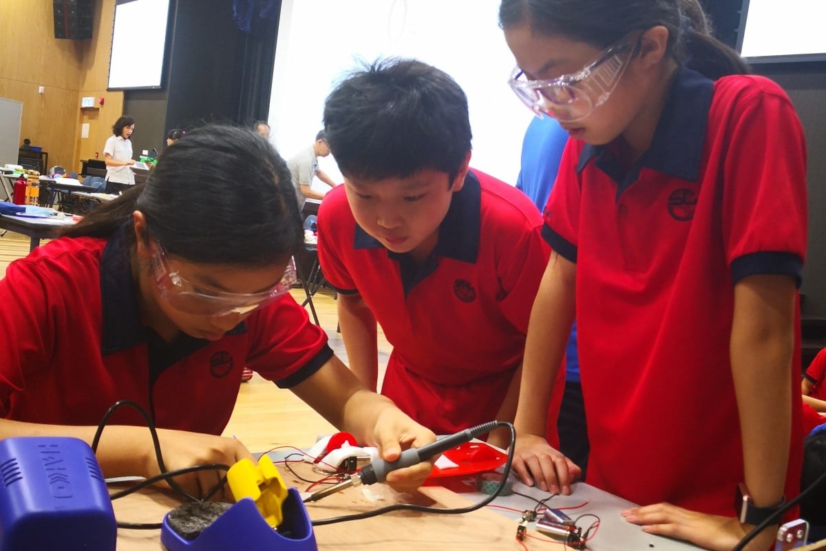 (From left) Jamie, Jared, and Nicole solder part of their motor's electrical circuit together.