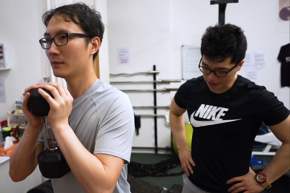 Personal trainer Mike Wong (right) shows YP's Jamie Lam how to do a goblet squat.