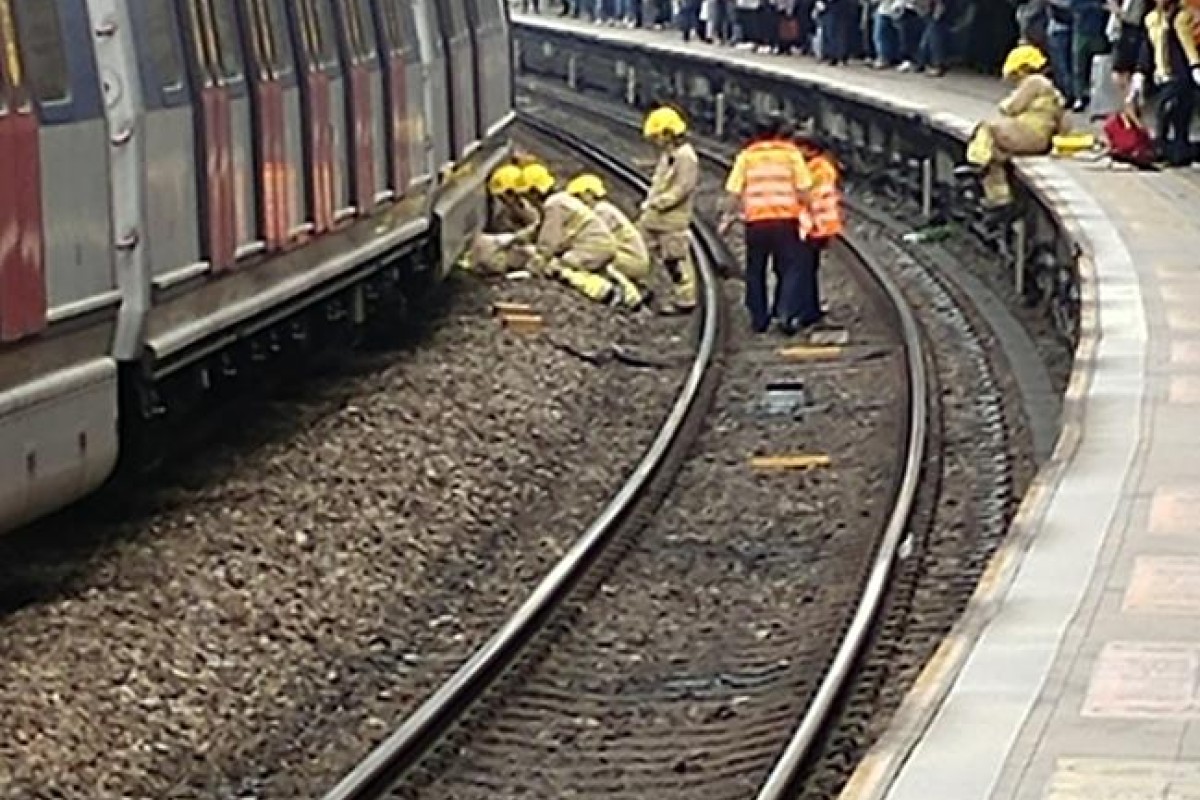 Firefighters rescue the woman who fell onto the tracks at Kowloon Tong station.