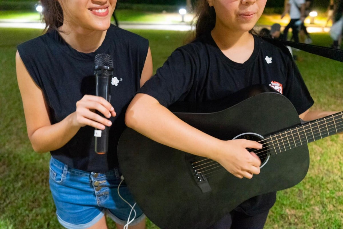Two young ladies, Li, 21, on the left and Ho, 20, sing a mix of hymns and pop songs at Tamar Park.