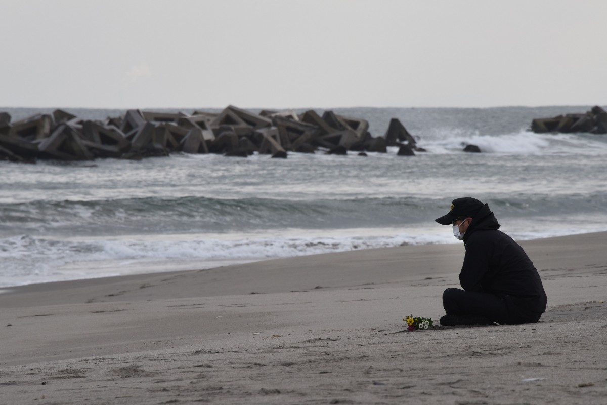 A man prays for victims of the 2011 earthquake and tsunami on a beach in Sendai, northern Japan on March 11, 2016.