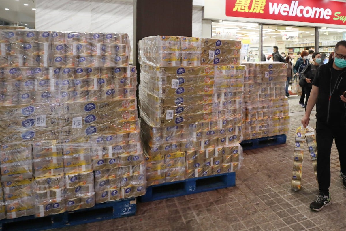 A man walks past new stock of toilet paper with his bags of toilet paper at Wellcome supermarket in Causeway Bay.
