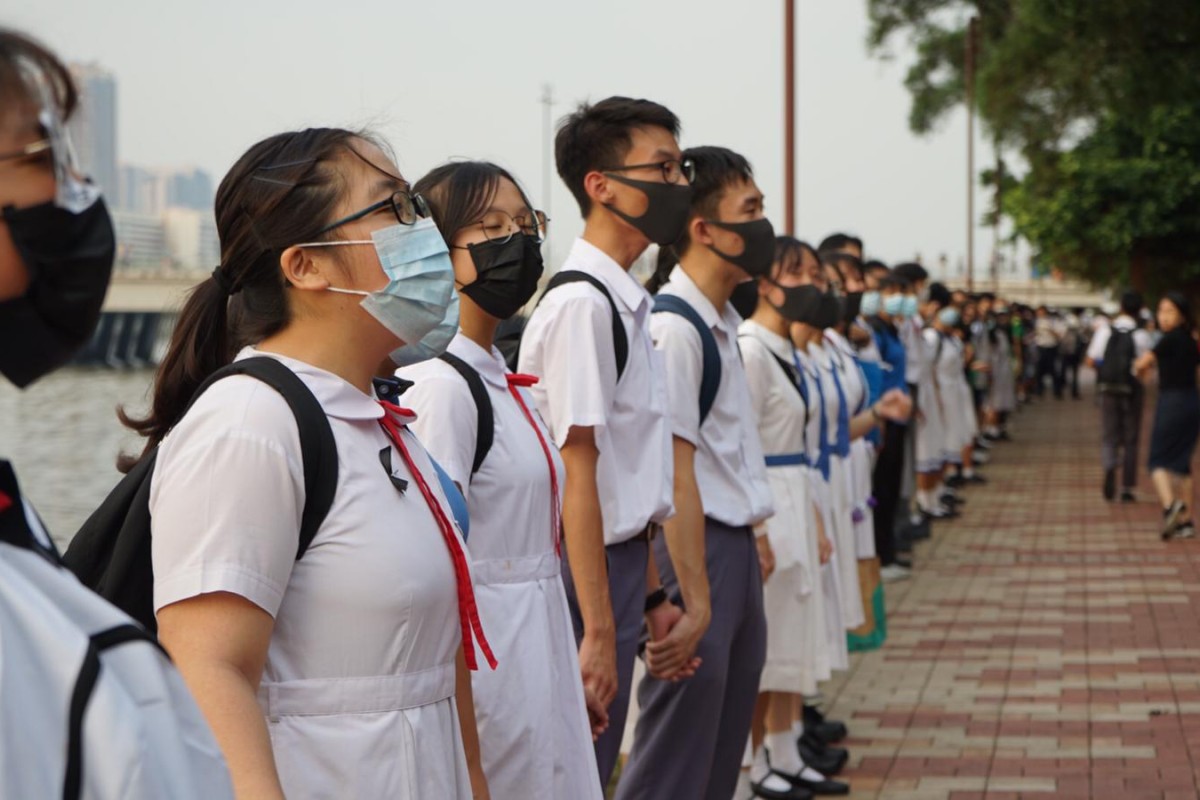 Masked students from 29 schools in Sha Tin join hands to form a human chain along Shing Mun River on Thursday.