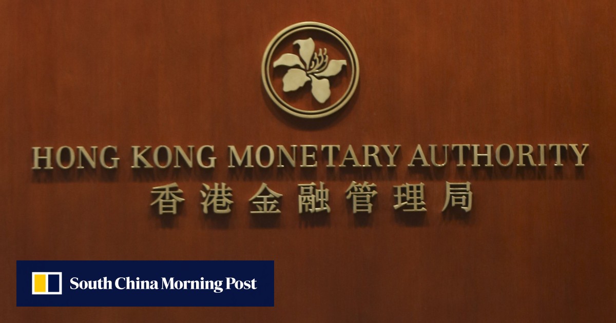 The image shows the logo and name of the Hong Kong Monetary Authority on a wooden wall, with a logo featuring a flower or plant design above the text, and a South China Morning Post watermark at the bottom left corner.