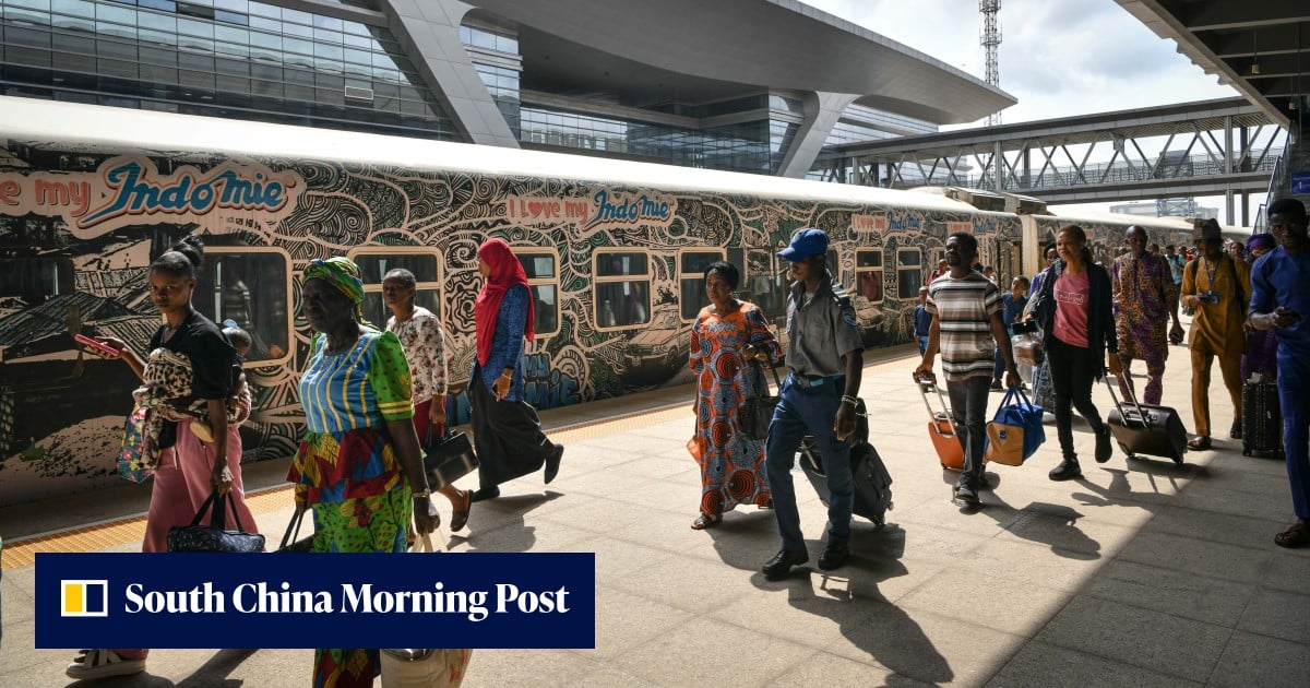 People walking through a modern airport terminal past an Indomie advertisement.