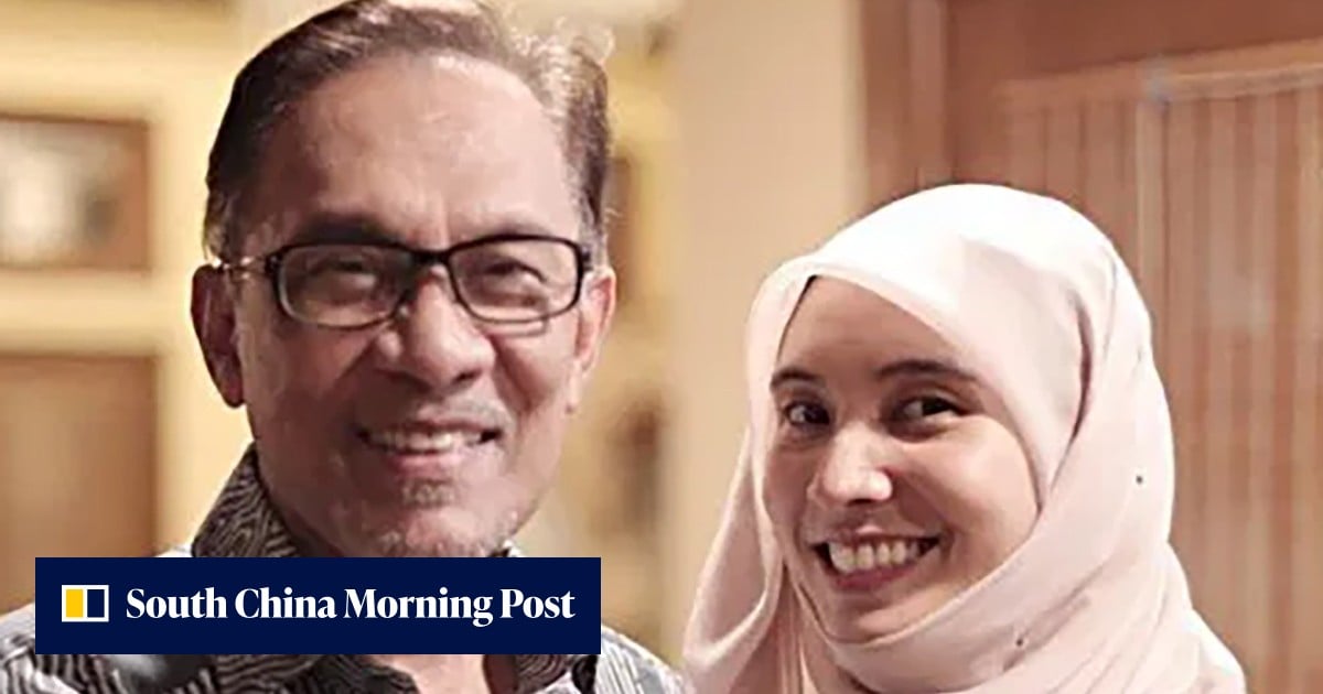 A man and a woman in a hijab smiling together indoors.