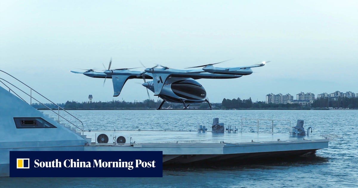 A helicopter hovers over a floating platform on the water near a city skyline.