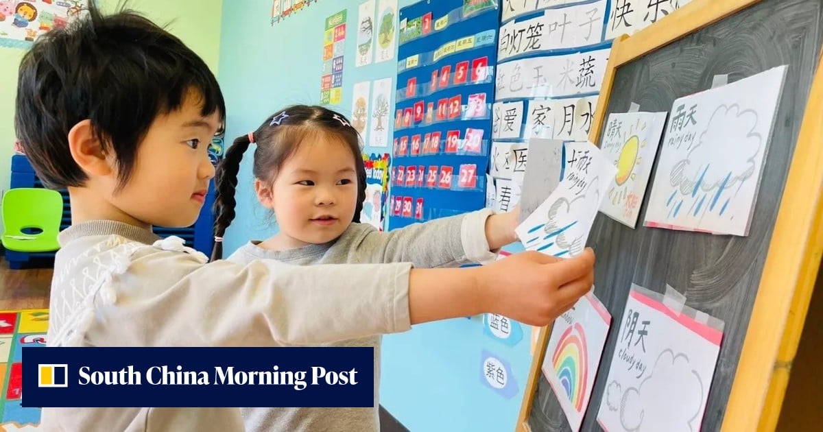 Two young children placing a weather drawing on a classroom chalkboard.