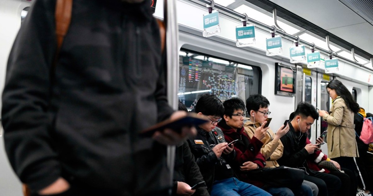 Students play online games inside a subway train in Beijing