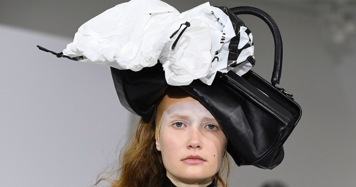 Models wearing a garbage bag dress with a trash can lid hat, a dry
