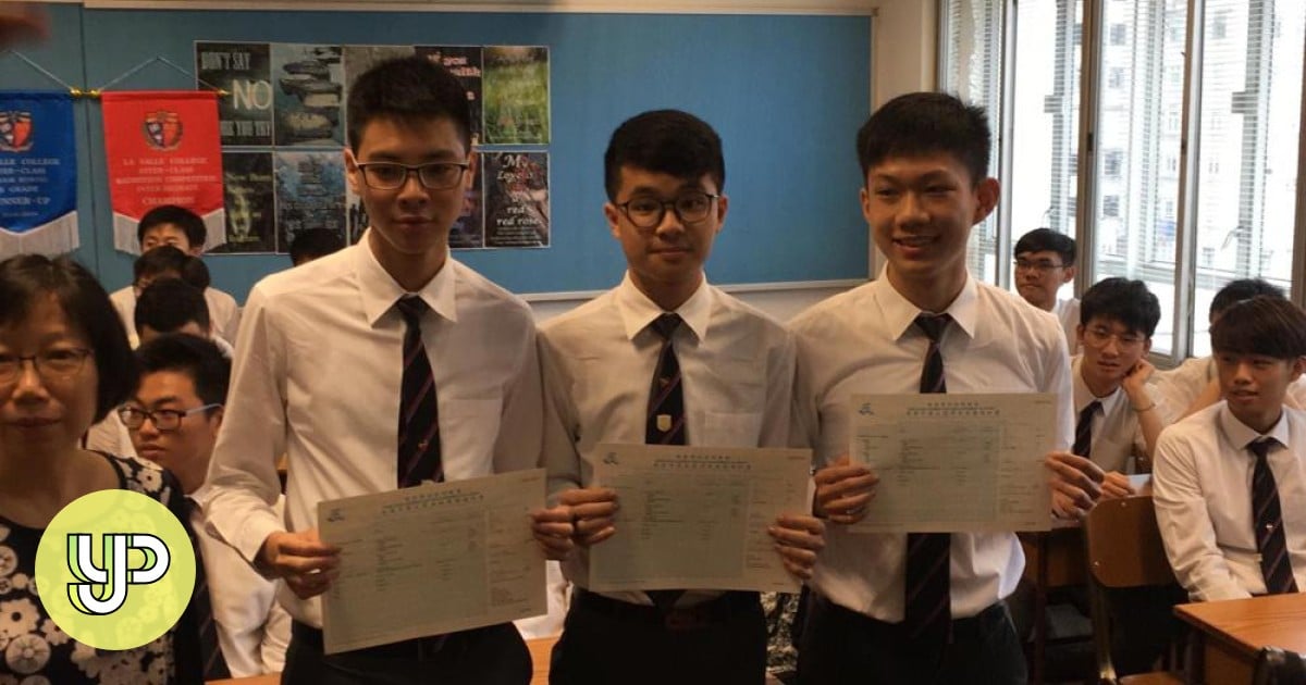 Three top-scoring students from Greater Bay Area schools are holding their exam results and are surrounded by peers and a teacher in a classroom celebrating their academic achievements.