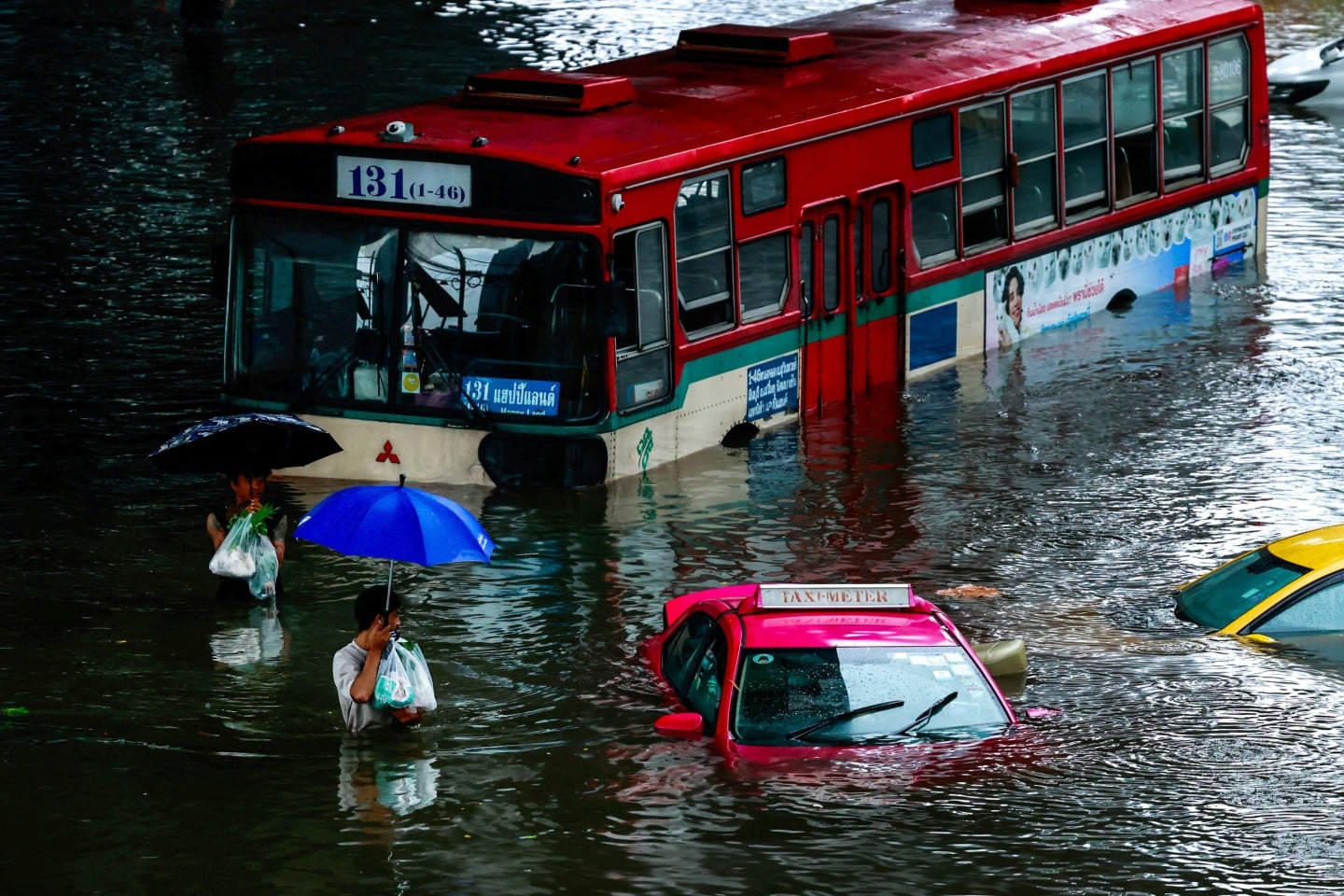 Bangkok residents wade through a flooded street beside submerged vehicles on September 26. Photo: Reuters