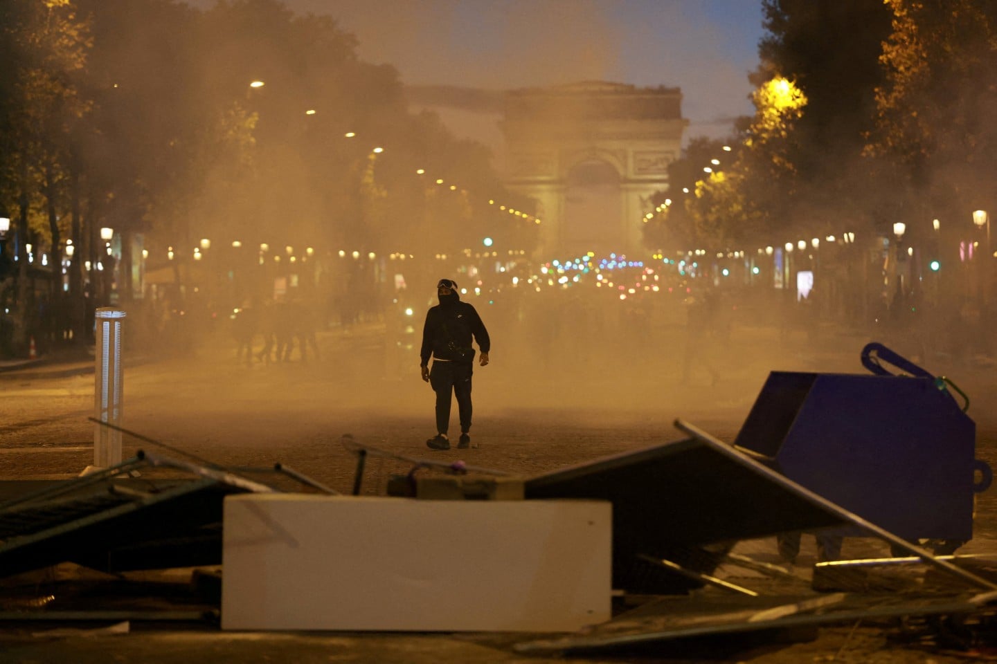 A protester walks through tear gas near a barricade on the Champs-Elysees avenue in Paris. Photo: Reuters